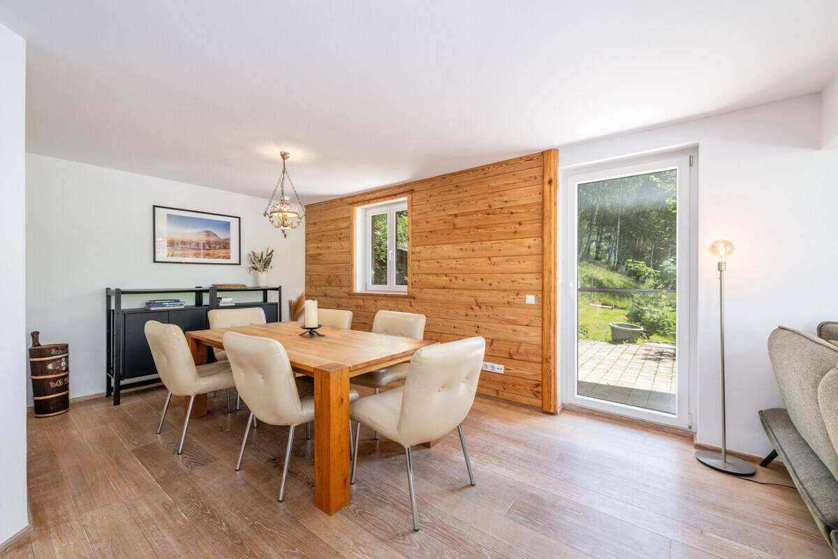 Heller Essbereich mit Holztisch, bequemen Stühlen und Holzwand, mit Zugang zum Außenbereich.