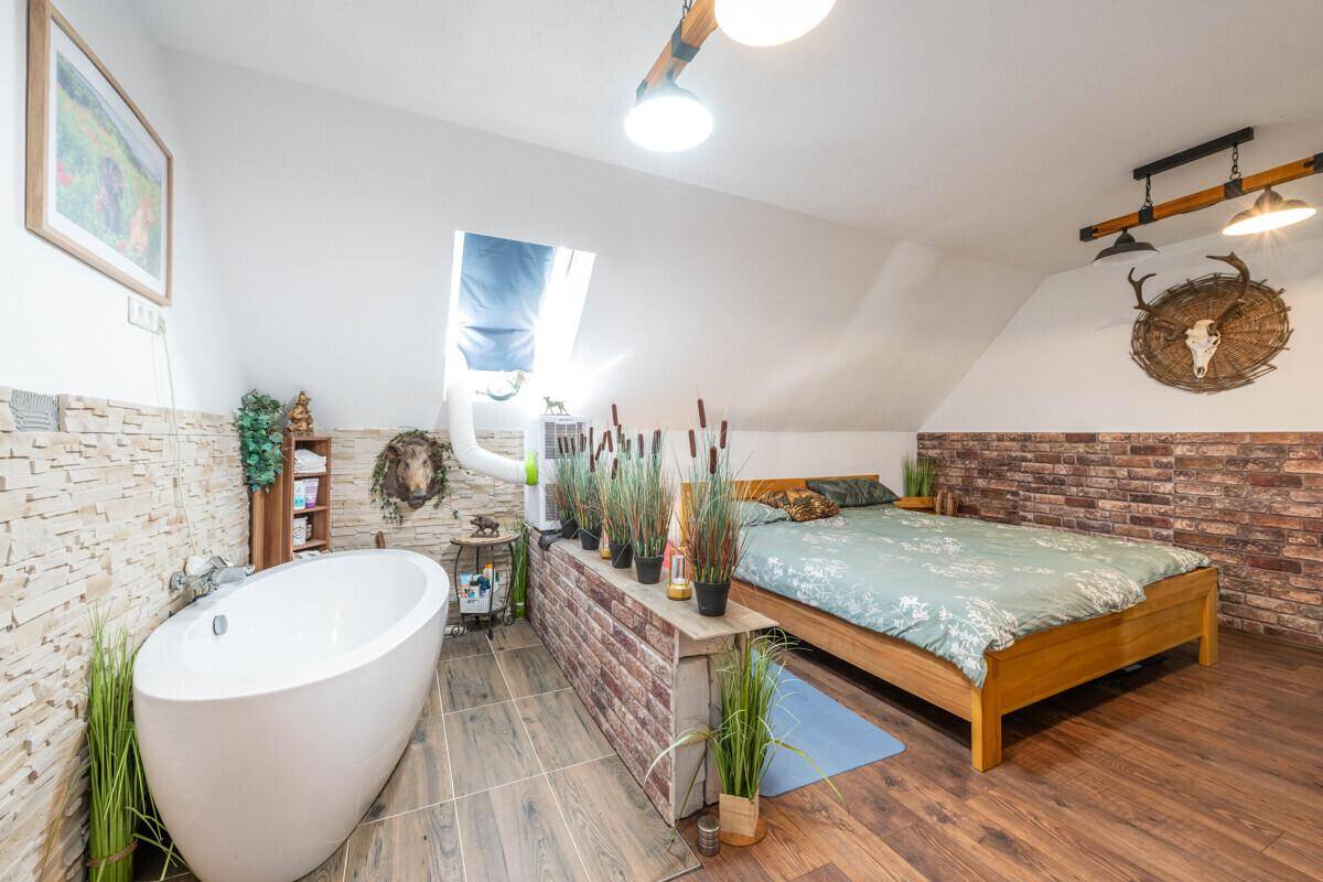 Geräumiges Schlafzimmer mit freistehender Badewanne, Holzbett und rustikalen Akzenten.