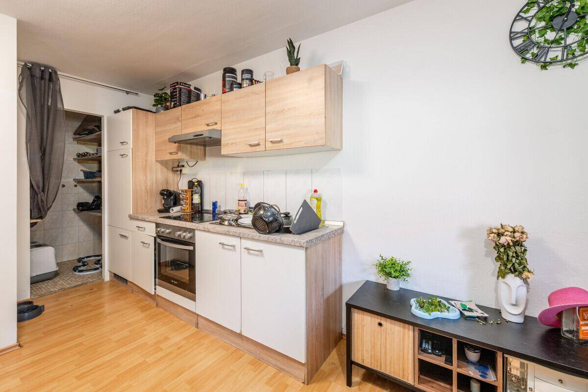 Kleine Küchenzeile mit Kochfeld und Backofen in einem hellen Raum mit Laminatboden, funktional und kompakt.