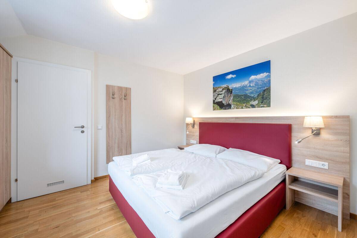 Schlafzimmer mit Doppelbett, Nachttischen und einem dekorativen Bild über dem Bett.