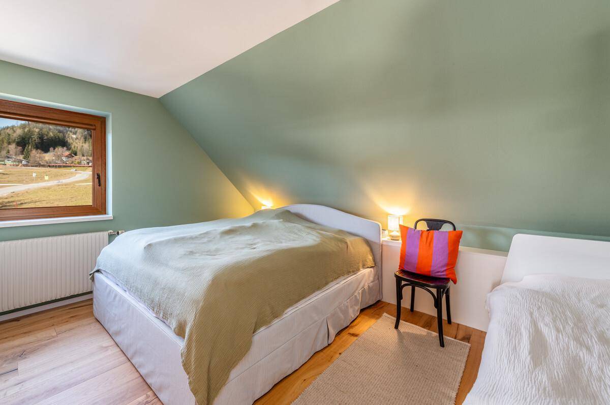 Schlafzimmer mit grünen Wänden, Holzboden und Fenster mit Blick auf die Landschaft.
