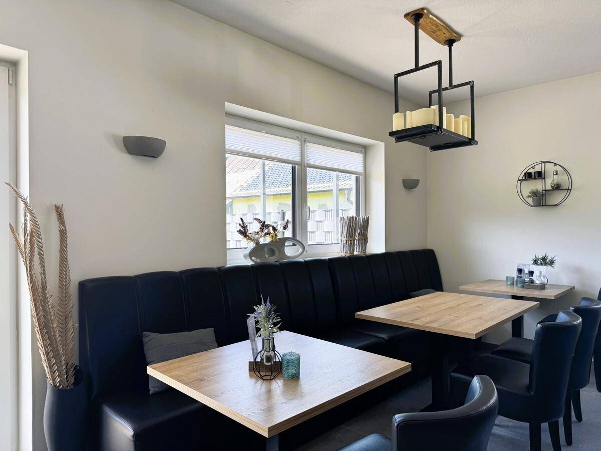 Gemütlicher Essbereich mit Sitzbänken, Holztischen und dekorativer Beleuchtung.