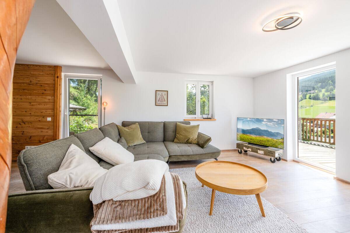 Gemütliches Wohnzimmer mit modernem Sofa, Holztisch und hellem Zugang zum Außenbereich.