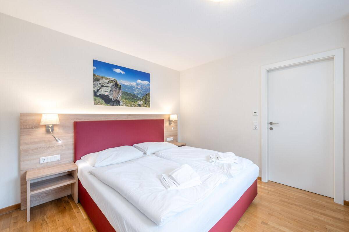 Gemütliches Schlafzimmer mit Doppelbett, Nachttischen und einem Wandbild als Dekoration.