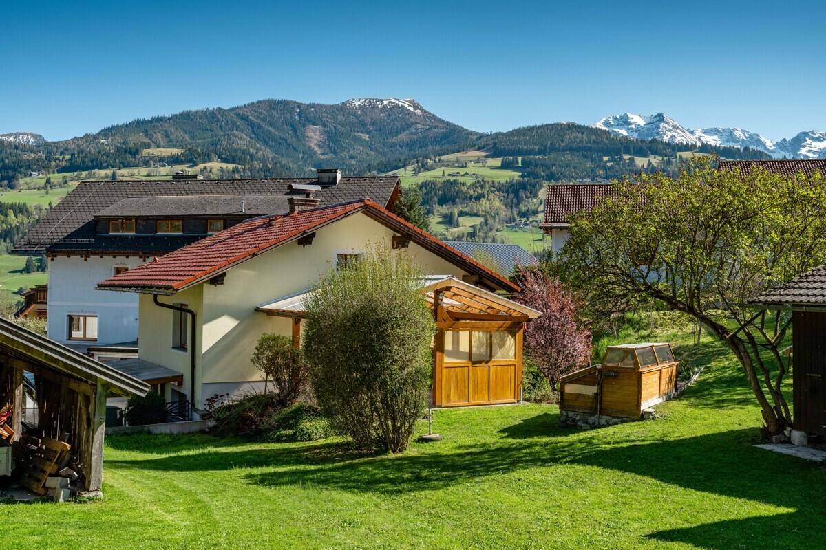 Weitläufiger grüner Garten mit Blick auf die umliegenden Berge und das Haus.