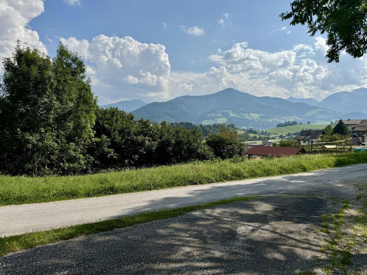 Panoramablick auf eine weite grüne Landschaft mit Bergen und einem Tal.