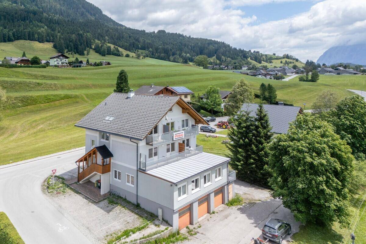 Luftaufnahme des Gebäudes mit Balkonen, Garagen und der idyllischen Berglandschaft.