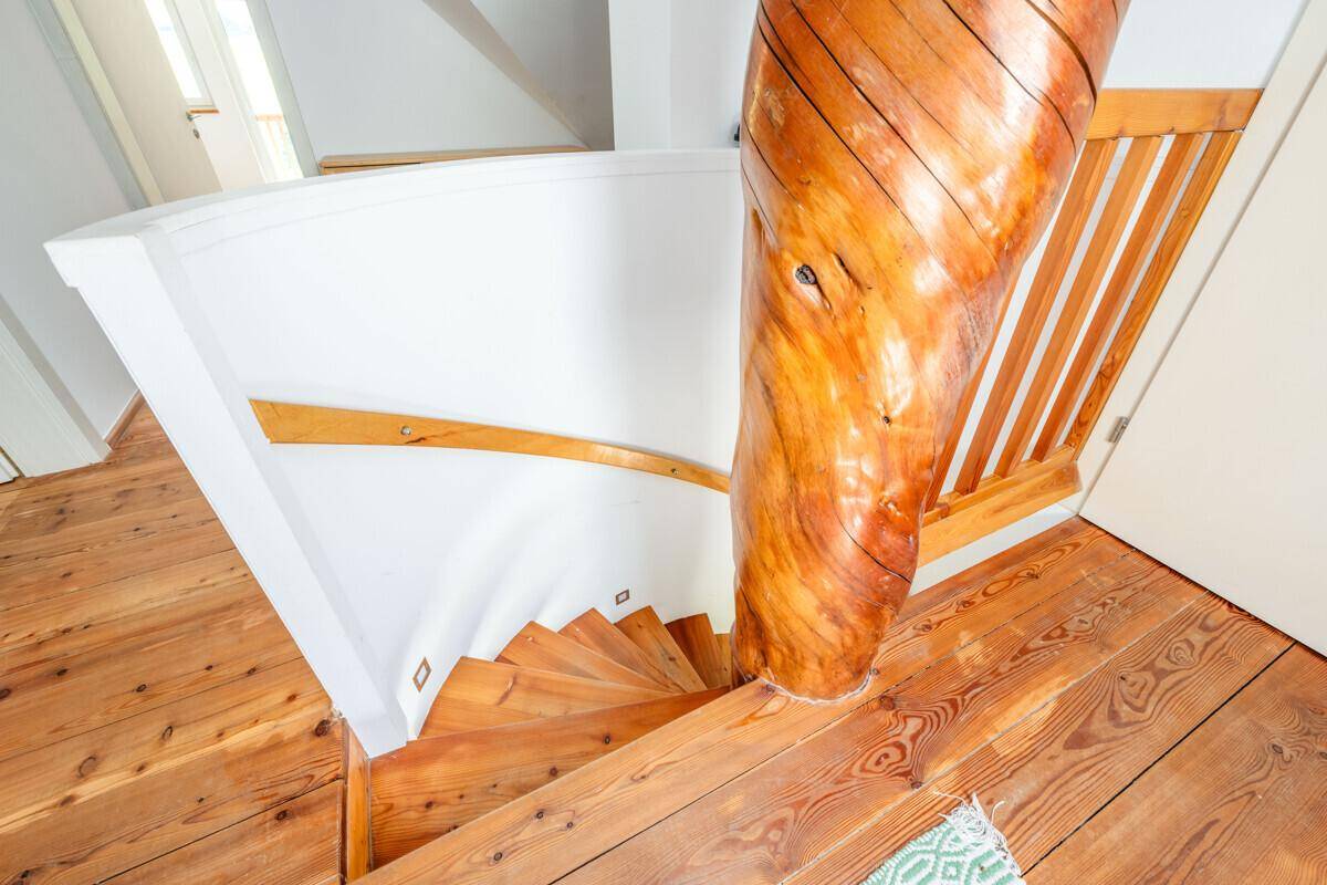 Rustikale Holztreppe mit markantem zentralem Holzpfosten und Holzboden.