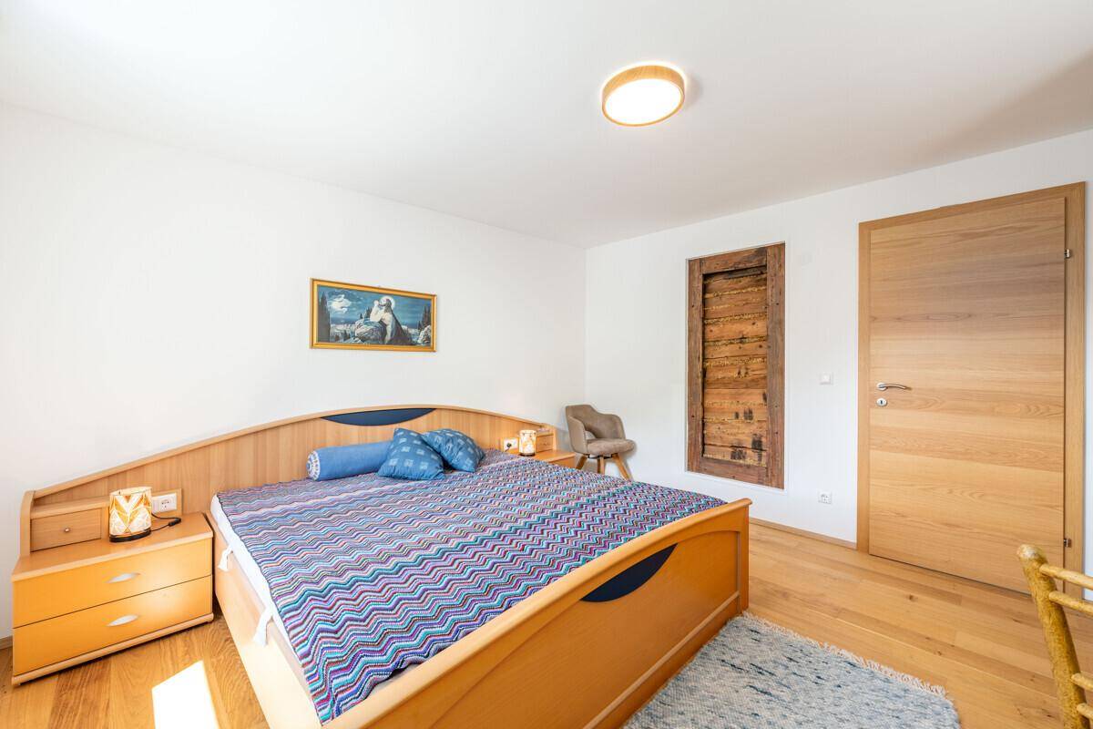 Helles Schlafzimmer mit Holzbett, Nachttischen und einem dekorativen Holzelement an der Wand.