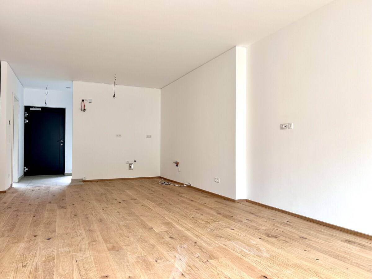 Heller, leerer Raum mit neuem Eichenparkettboden und weißen Wänden, bereit für die Einrichtung.