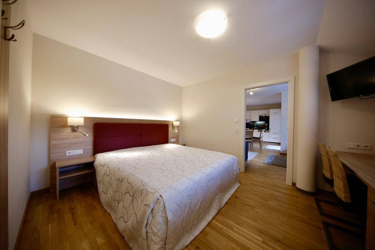 Helles Schlafzimmer mit Doppelbett, Holzboden und einem Holzkopfteil, das eine warme Atmosphäre schafft.