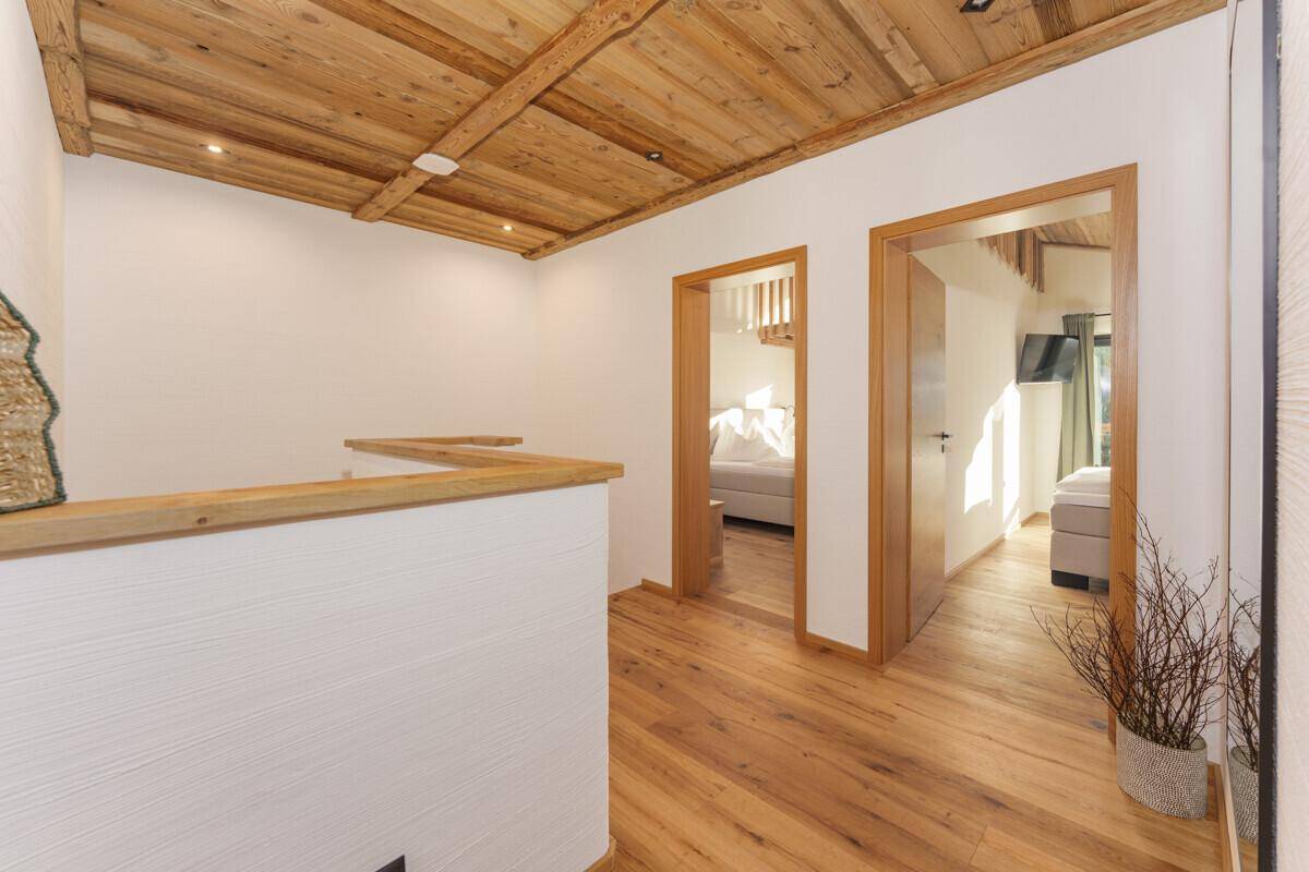 Heller Flur mit Holzboden, Holzbalkendecke und Zugang zu den Schlafzimmern.
