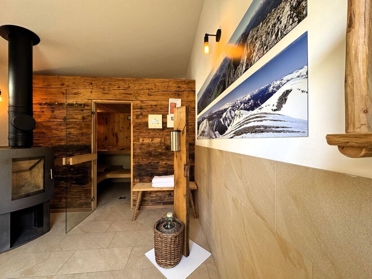 Entspannender Wellnessbereich mit holzverkleideter Sauna und modernem Kaminofen, ideal zum Erholen.