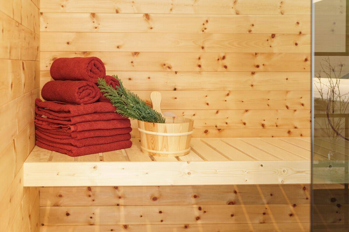 Holzvertäfelte Sauna mit Bänken, Eimer und Handtüchern für entspannende Momente.