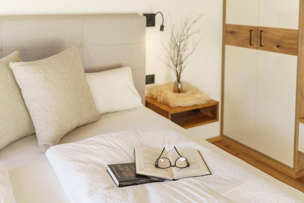 Helles Schlafzimmer mit modernem Bett, schwebendem Nachttisch und Holzelementen.