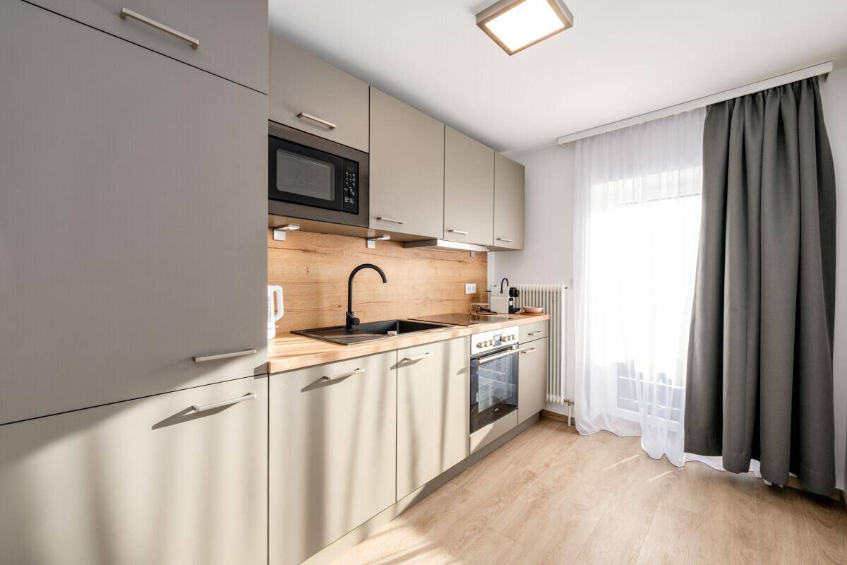 Moderne Küchenzeile mit grauen Schränken, Holzarbeitsplatte und Fenster.