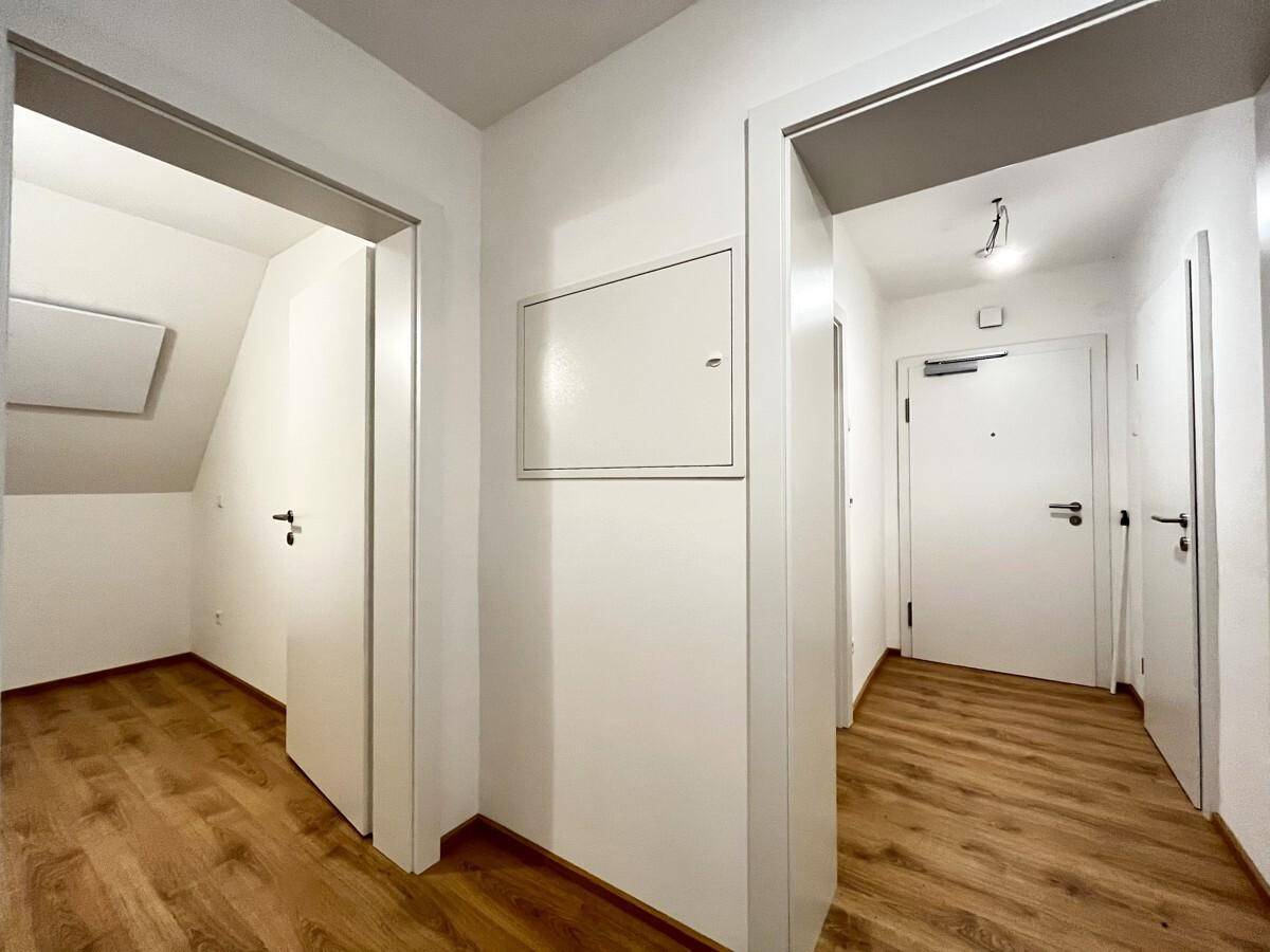 Heller Flur mit Laminatboden und weißen Türen, der Zugang zu verschiedenen Räumen bietet.
