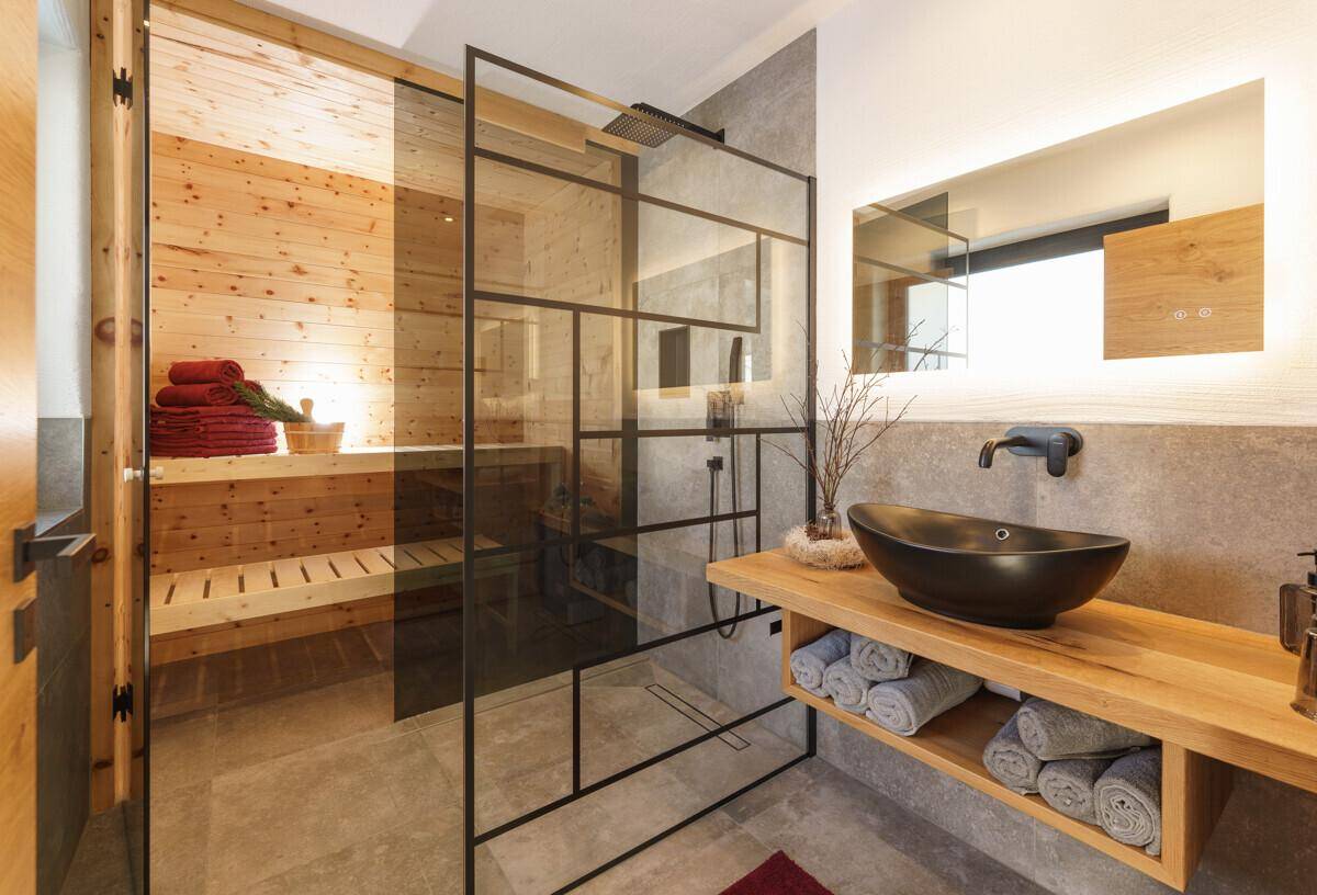 Luxuriöses Badezimmer mit Sauna, begehbarer Dusche und modernem Waschtisch.
