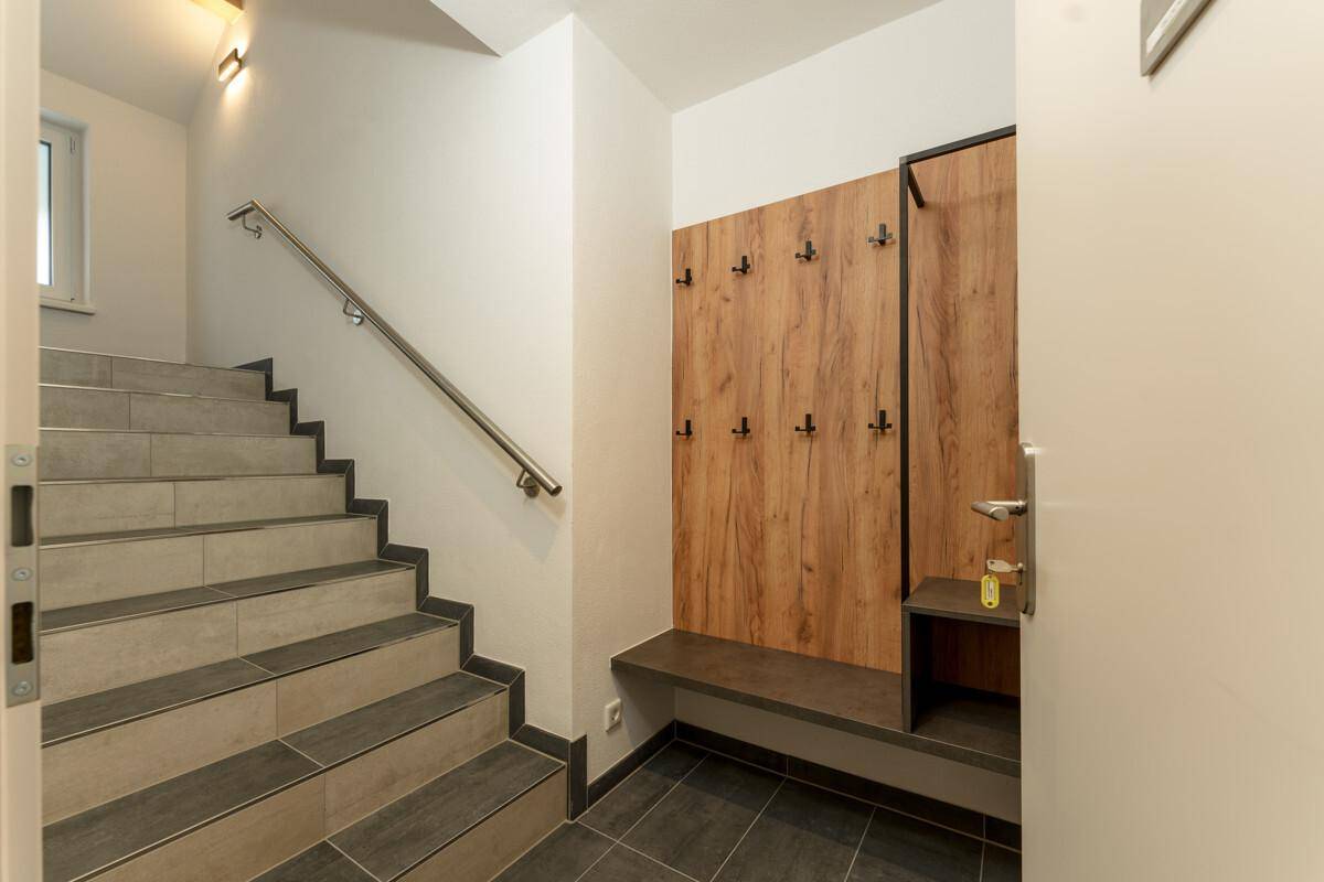 Eingangsbereich mit Garderobe, Sitzbank und Treppe mit Fliesenboden.