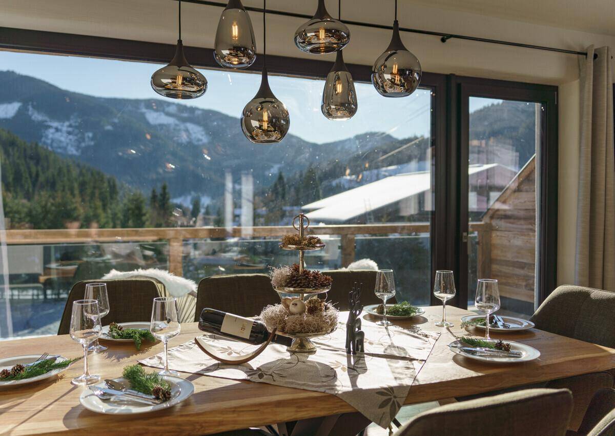 Esstisch mit stilvoller Beleuchtung und Panoramablick auf die verschneite Berglandschaft.