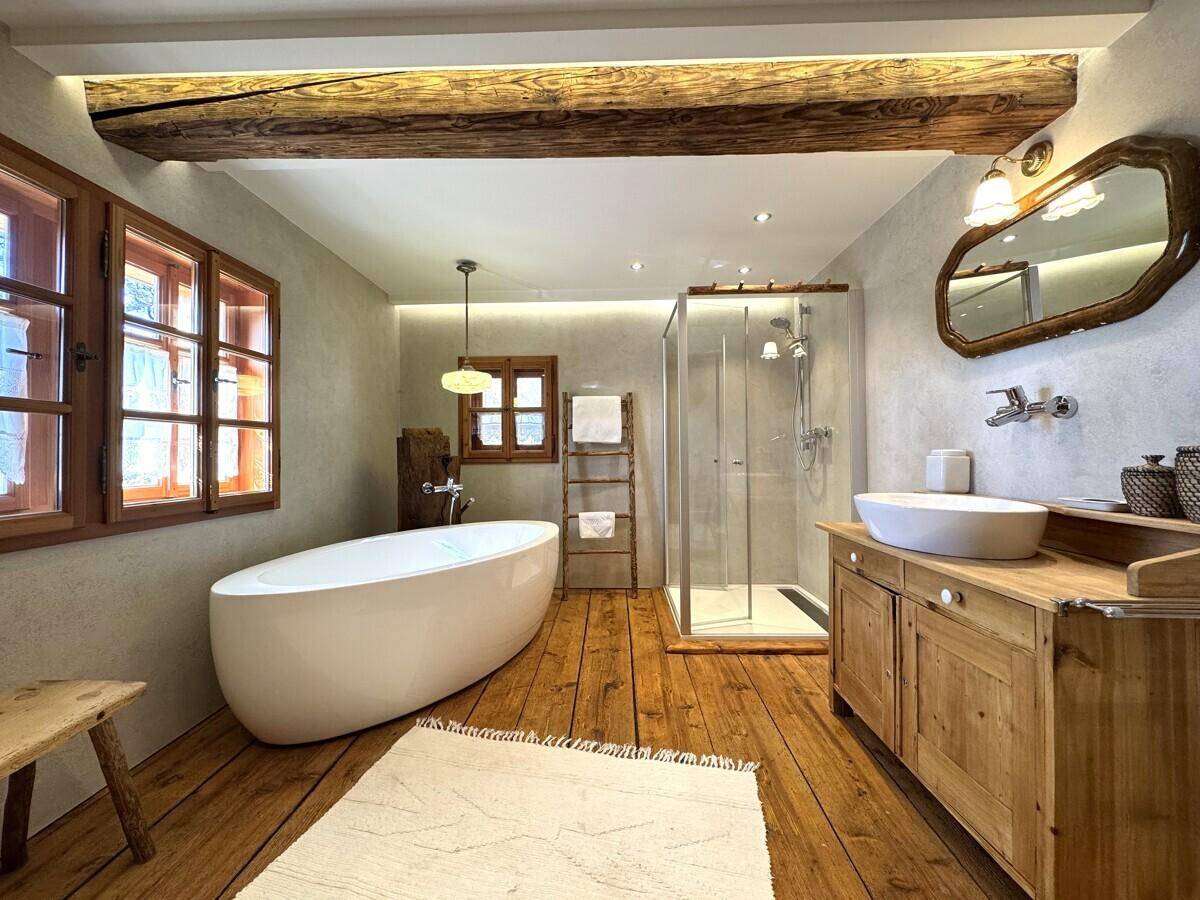 Geräumiges Badezimmer mit freistehender Badewanne, moderner Dusche und rustikalem Holzwaschtisch.