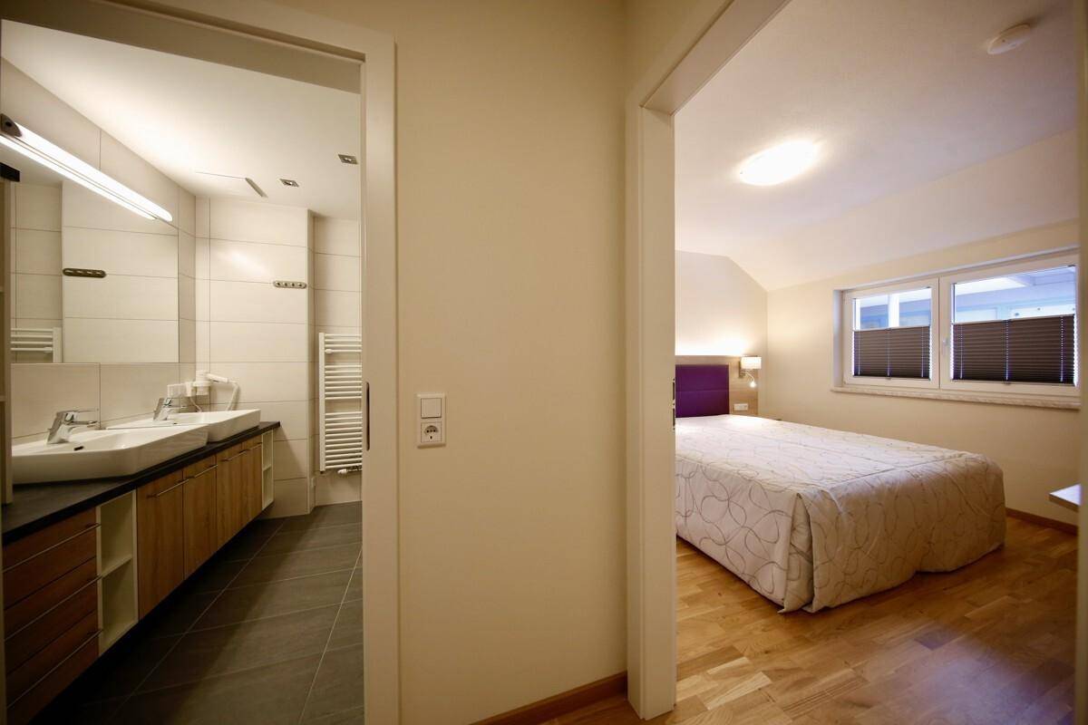 Heller Flur mit Holzboden, der zu einem Badezimmer und einem Schlafzimmer führt.