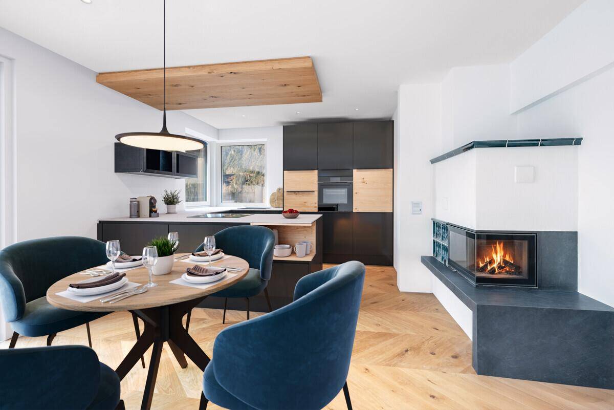 Moderne offene Küche mit Essbereich, Holzboden und integriertem Kamin.