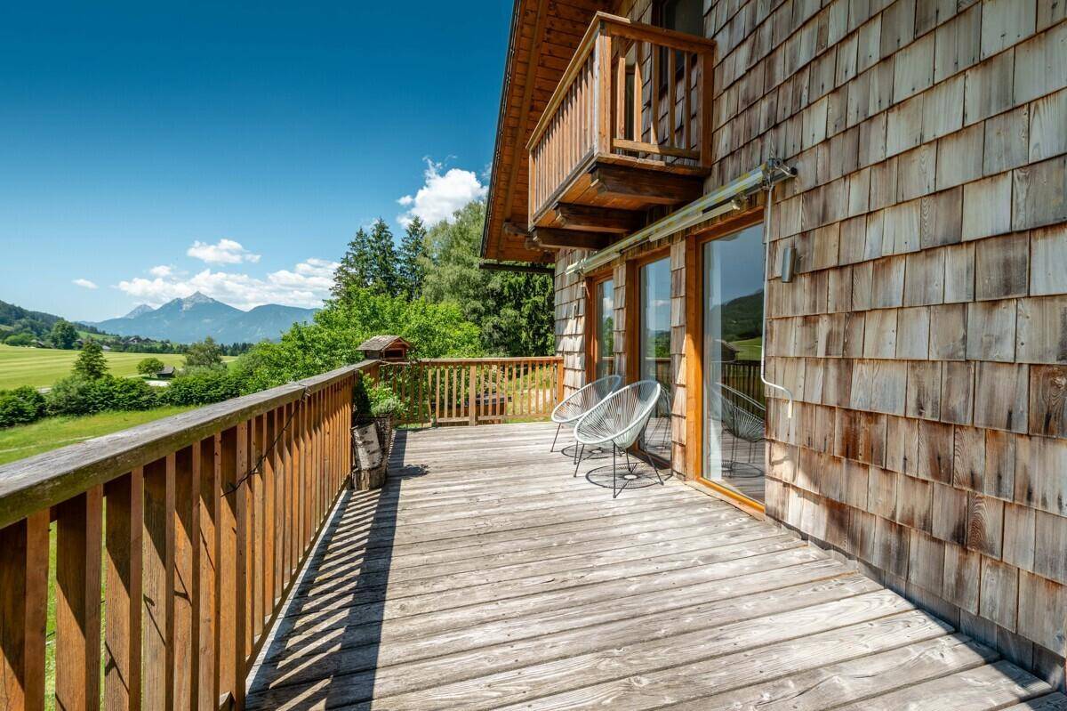 Großer Holzbalkon mit traditioneller Holzfassade und Panoramablick auf die umliegende Natur.