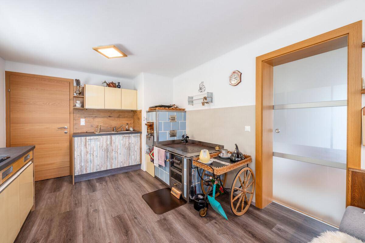 Funktionale Küche mit traditionellem Kachelofen und Holzmöbeln im Landhausstil.