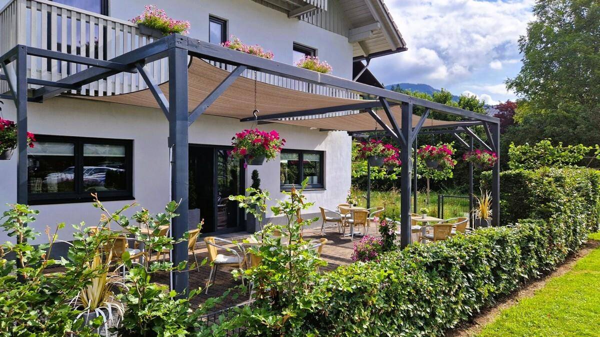 Gemütliche überdachte Terrasse mit Gartenmöbeln und blühenden Blumenkörben, ideal zum Entspannen.