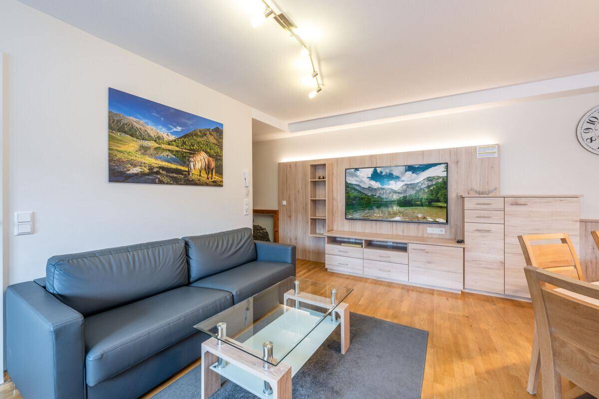 Gemütlicher Wohnbereich mit Sofa, Couchtisch und Medieneinheit, offen zum Essbereich.