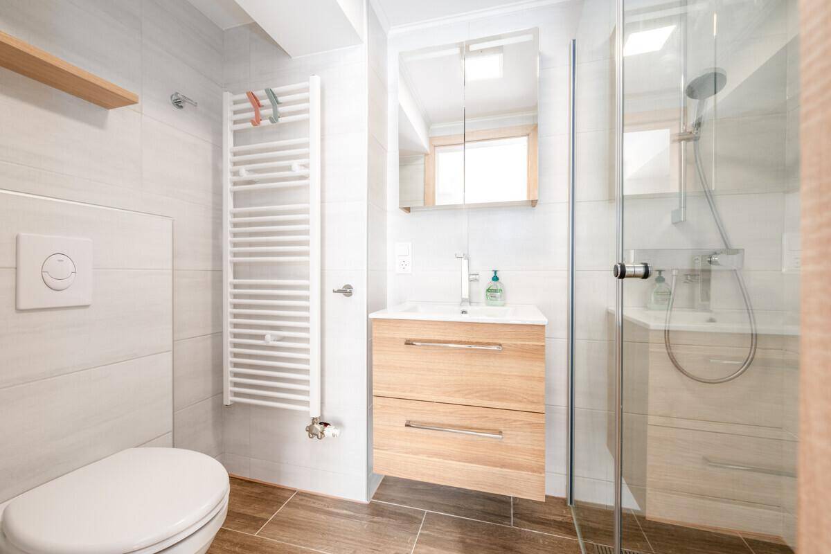 Modernes Badezimmer mit Dusche, wandhängendem WC und beheiztem Handtuchhalter.