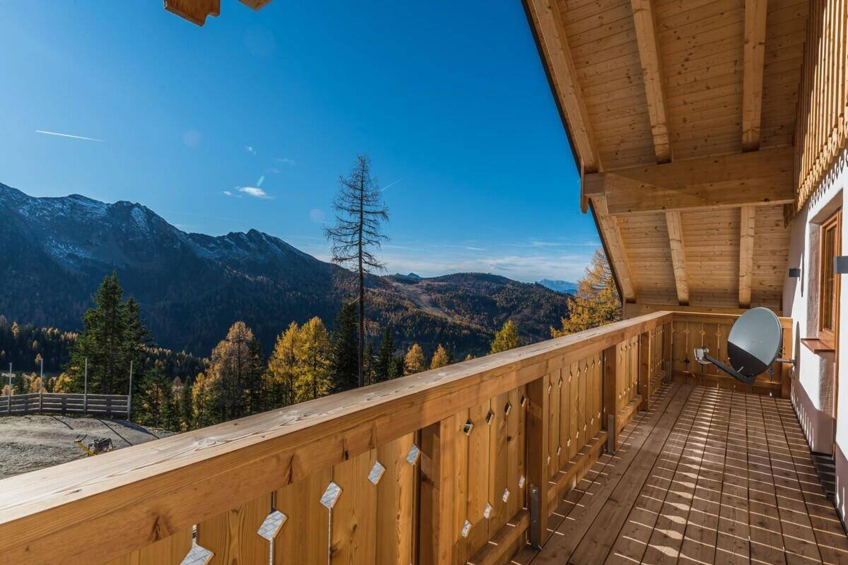 Geräumiger Holzbalkon mit geschnitztem Geländer und weitem Blick auf die Berglandschaft.