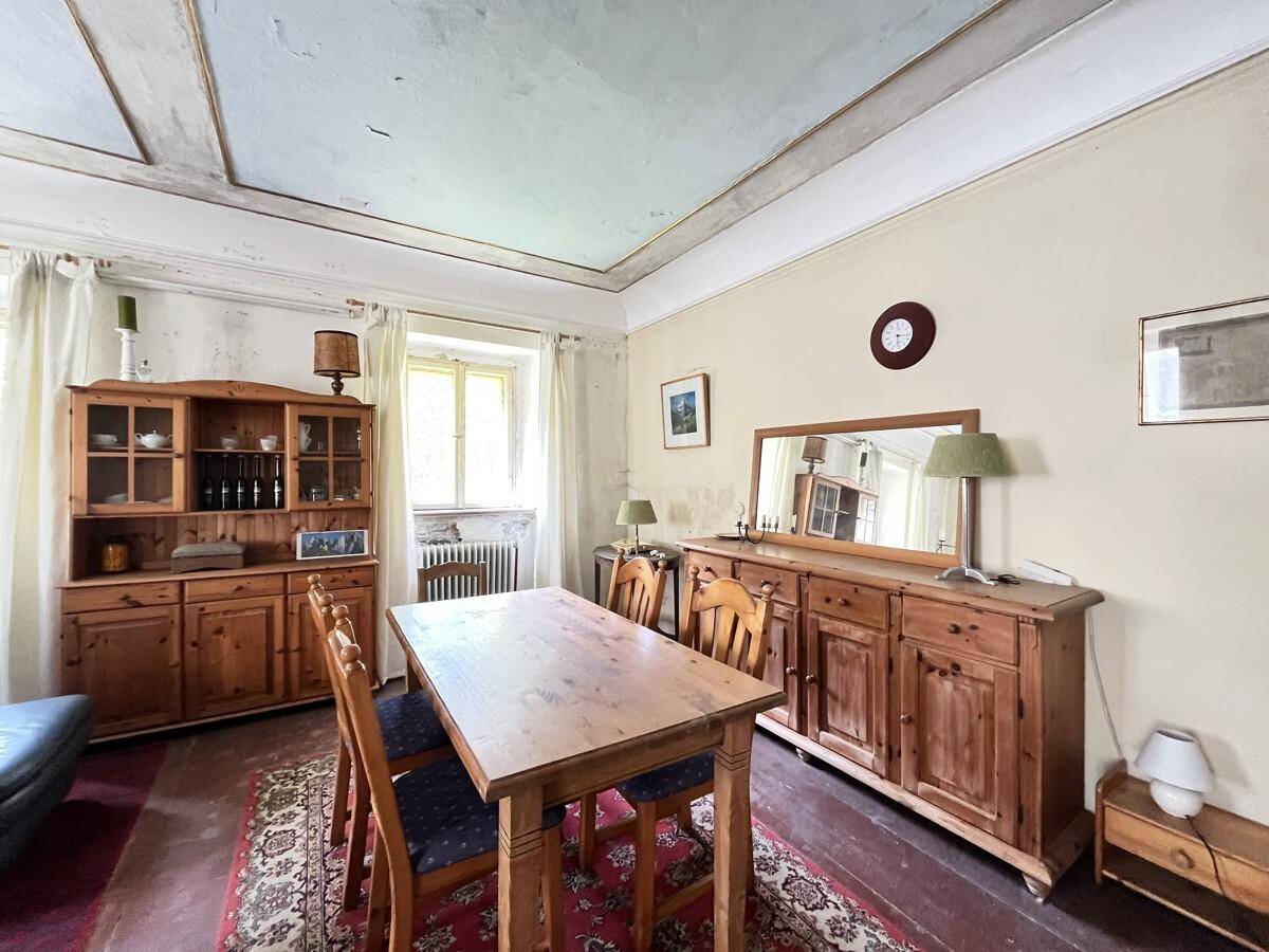 Traditioneller Essbereich mit Holztisch, Stühlen und einem großen Holzschrank.