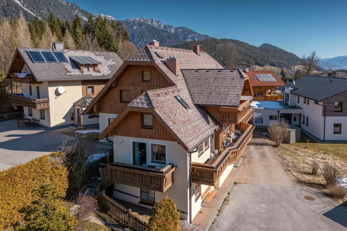 Vogelperspektive eines traditionellen Gebäudes mit Holzbalkonen und angrenzenden Häusern.