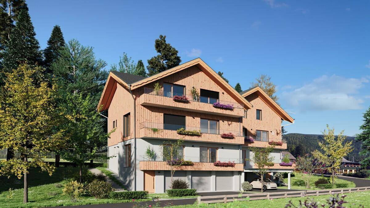 Ansicht des Neubaus im Chalet-Stil mit Holzverkleidung, Balkonen und integriertem Carport.