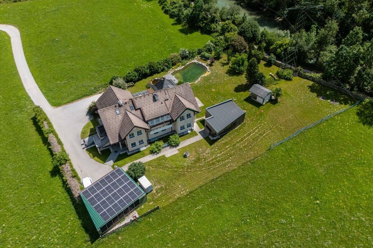 Luftaufnahme des Anwesens mit Photovoltaikanlage, Teich und umliegender Natur.