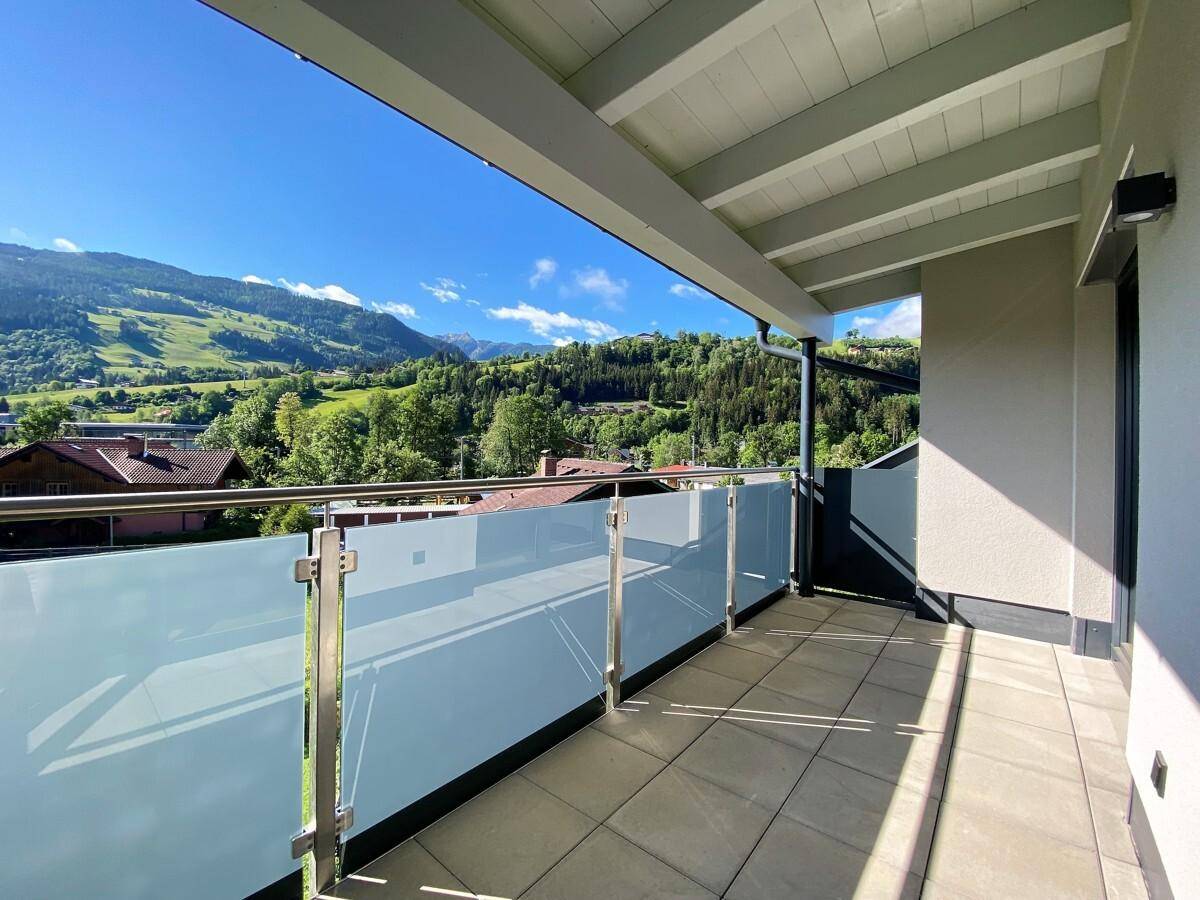 Geräumiger Balkon mit Fliesenboden und weitem Blick auf die umliegenden Berge.