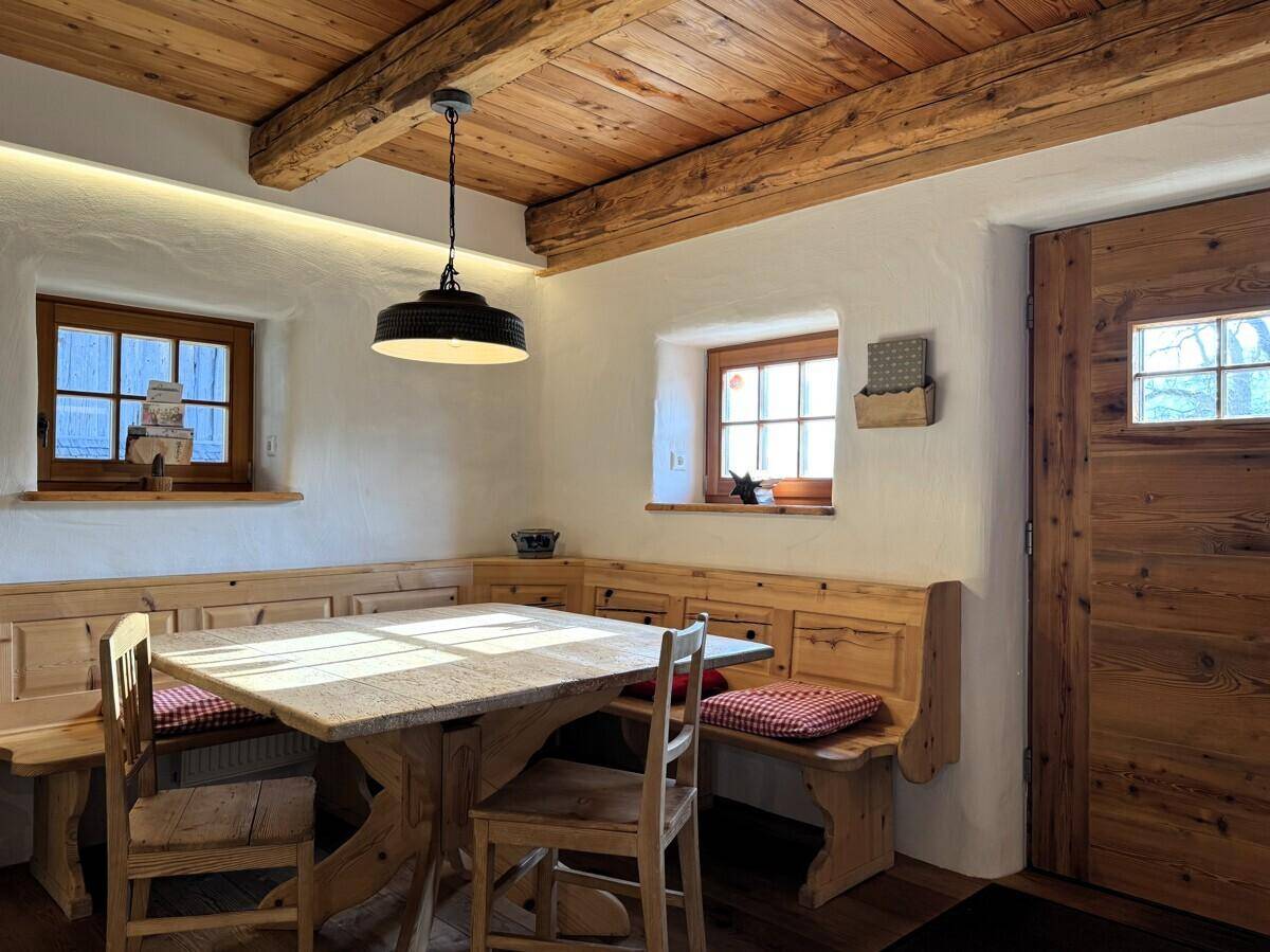 Gemütlicher Essbereich mit großem Steintisch und eingebauten Holzbänken, umgeben von warmem Holz.