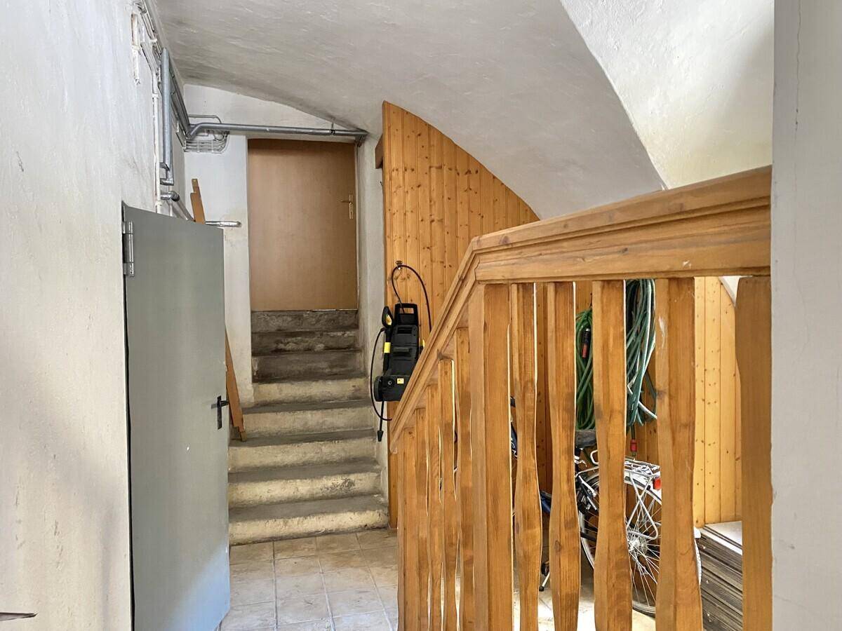 Treppenaufgang im Kellerbereich mit Holzgeländer und Zugang zu weiteren Räumen, funktional gestaltet.