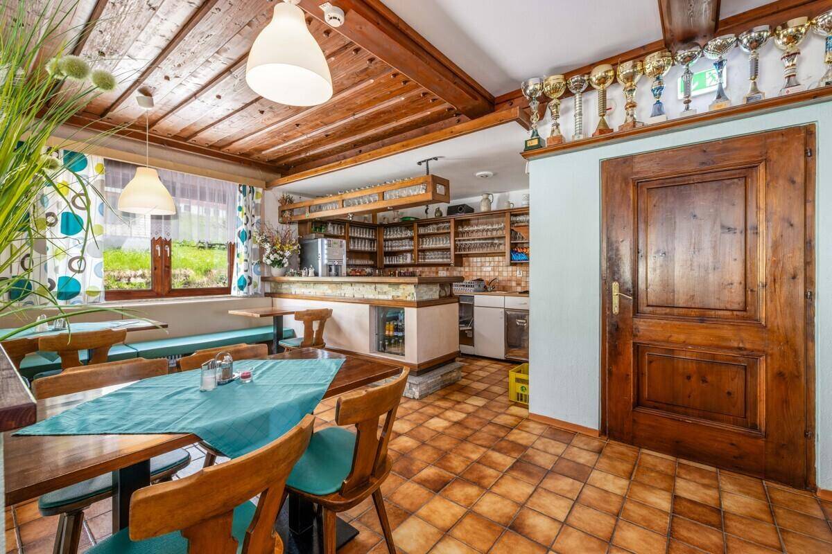 Traditioneller Essbereich mit Holzbalkendecke, Fliesenboden und einer Bar mit zahlreichen Trophäen.