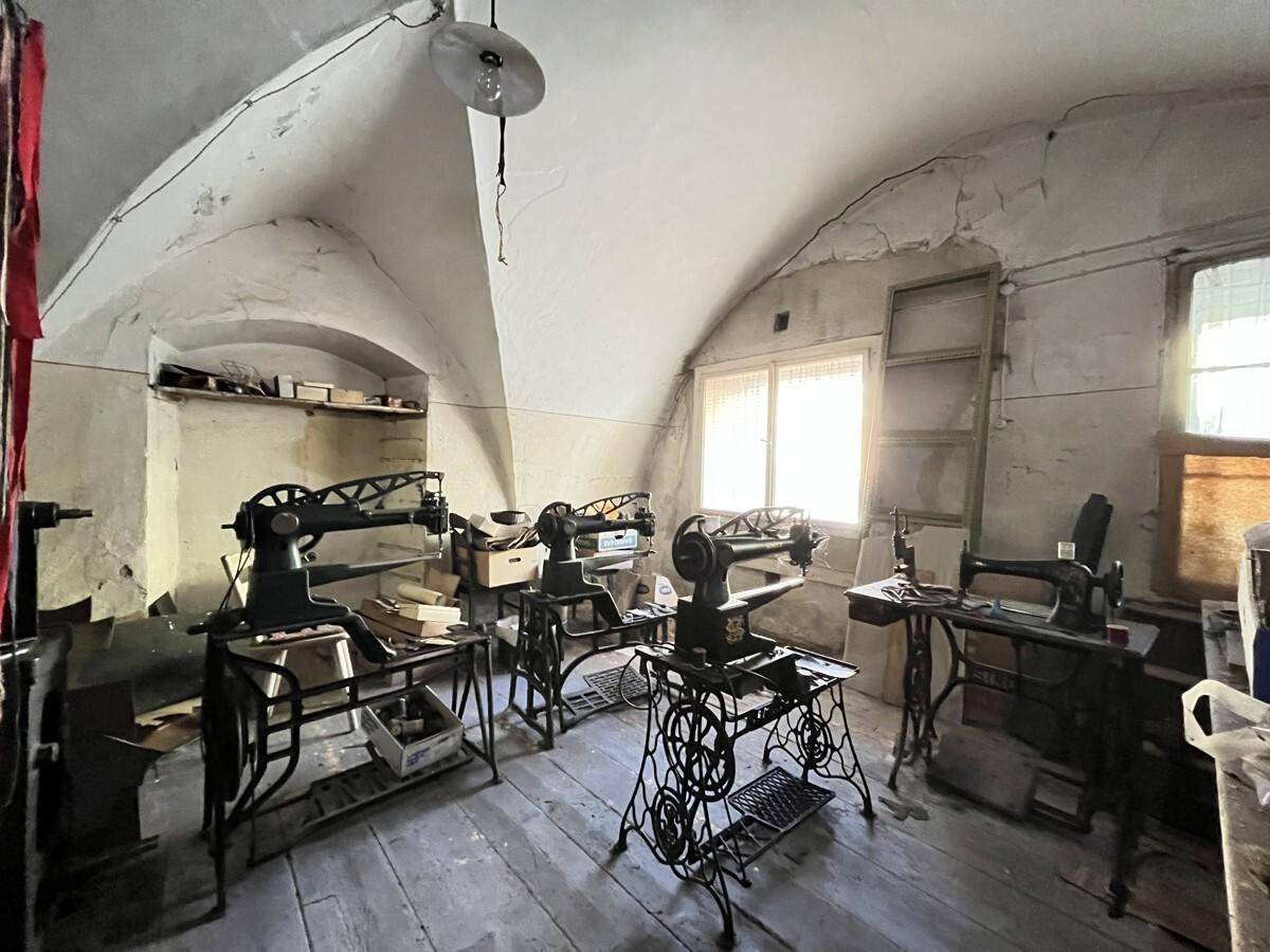 Werkstattraum mit gewölbter Decke, Holzboden und mehreren antiken Nähmaschinen, die auf eine frühere Nutzung hinweisen.