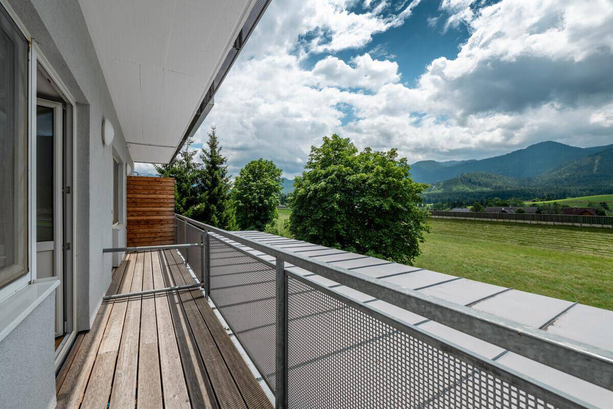 Geräumiger Balkon mit Holzboden und weitem Blick auf die umliegende Berglandschaft.