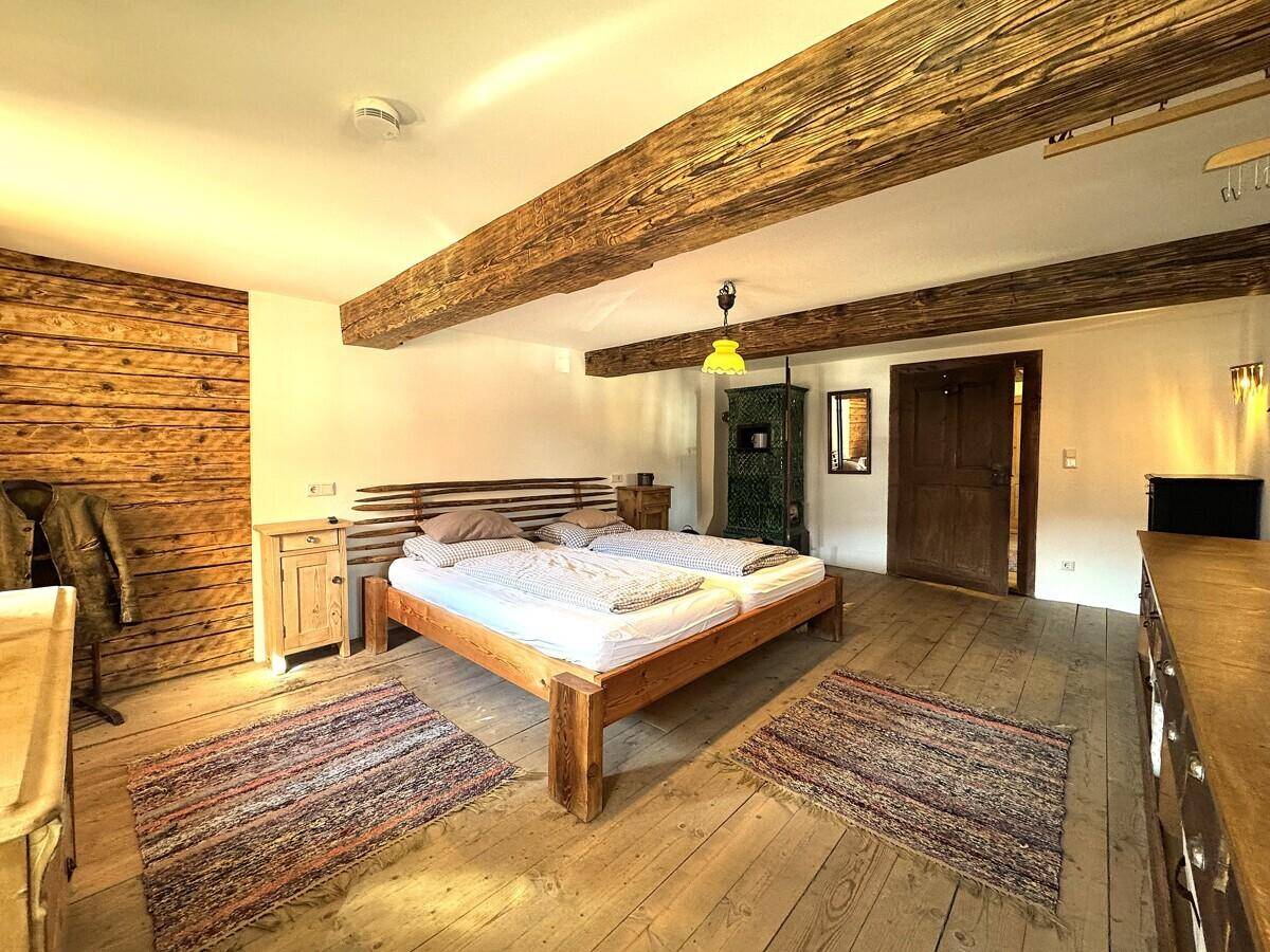 Gemütliches Schlafzimmer mit Holzbett, Holzdielenboden und sichtbaren Deckenbalken, traditionell eingerichtet.