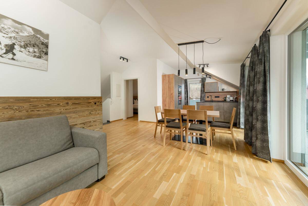 Heller Wohn- und Essbereich mit Holzboden, moderner Einrichtung und Zugang zum Balkon.