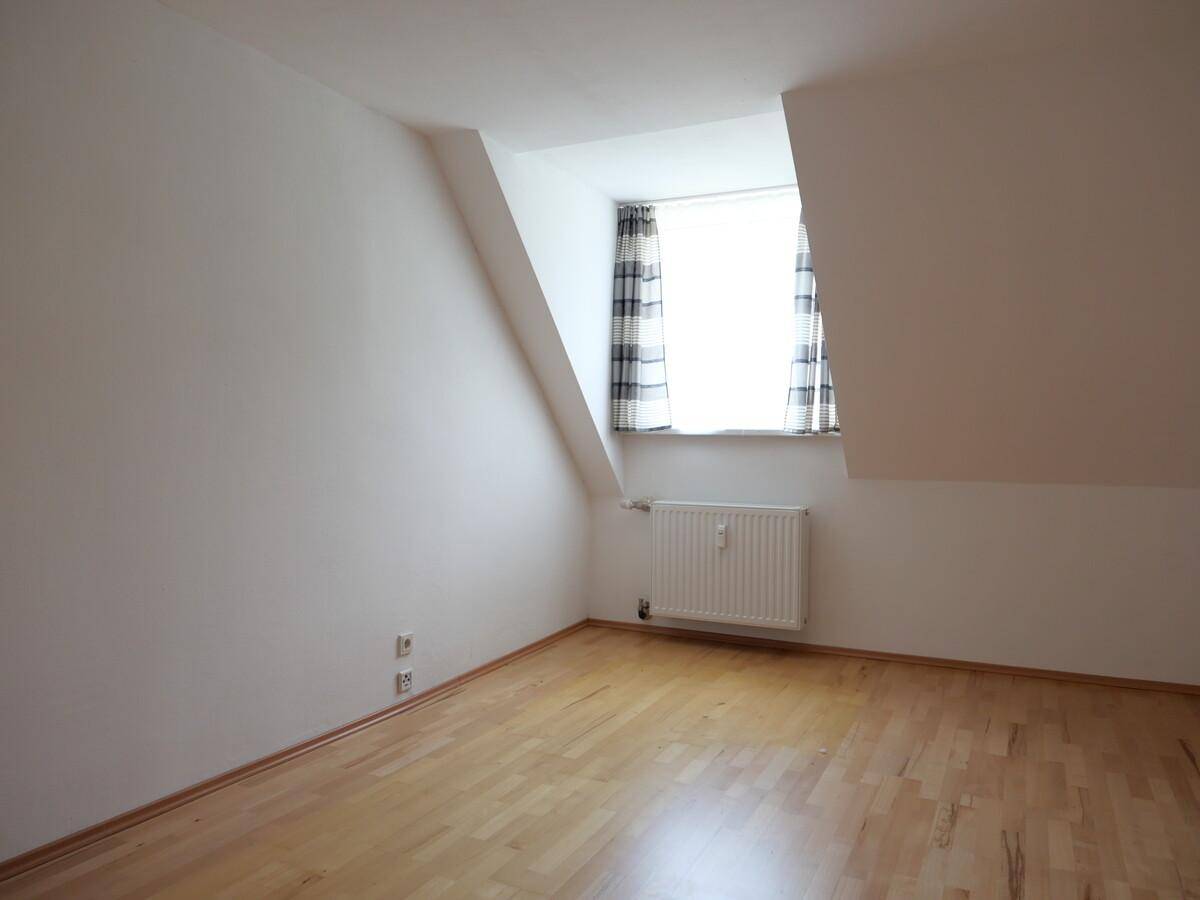 Heller Raum mit Dachschräge, Fenster und Heizkörper, bereit zur individuellen Gestaltung.