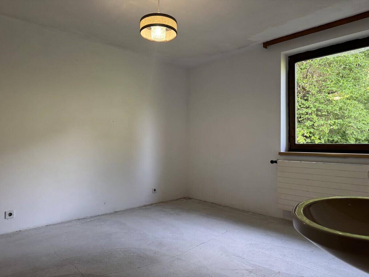 Leerer Raum mit hellem Boden, Fenster und einem Waschbecken in der Ecke.