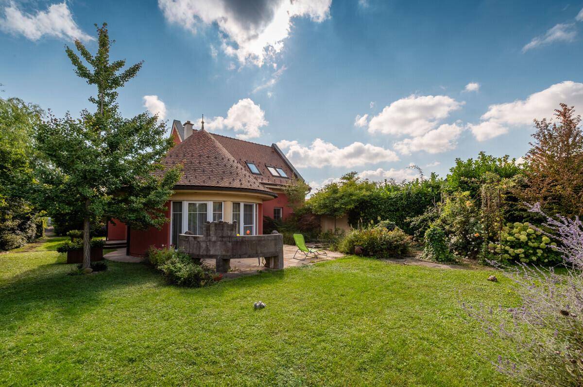 Rückansicht des Hauses mit weitläufigem Rasen, Garten und einer kleinen Terrasse.