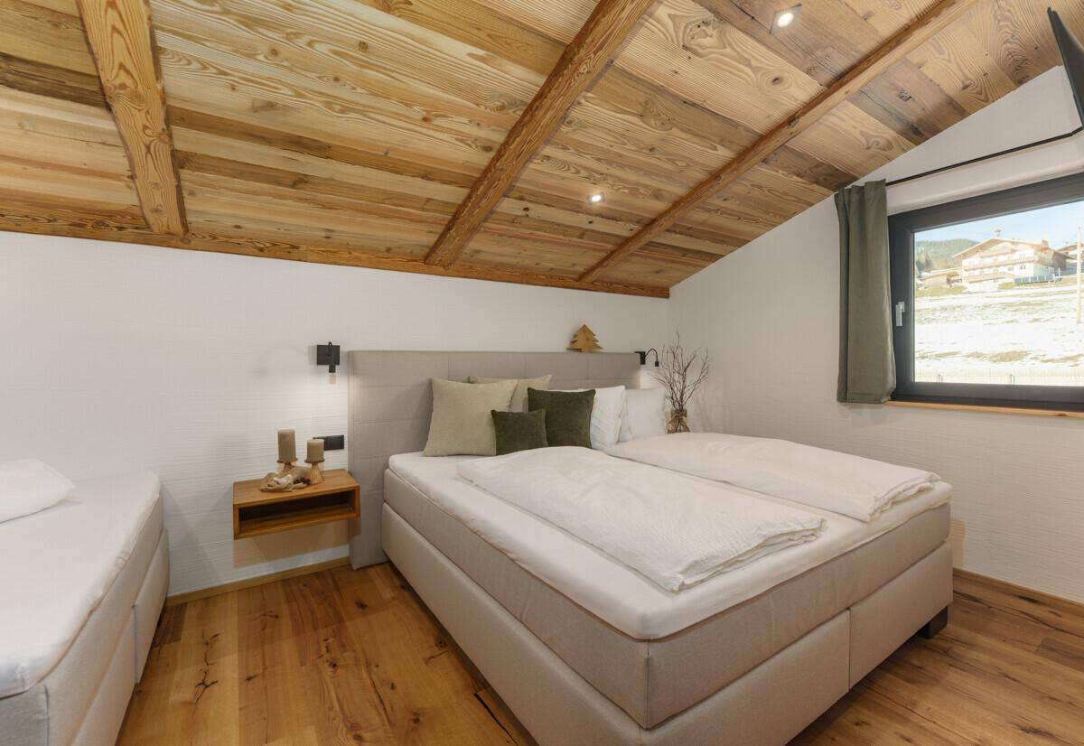 Gemütliches Schlafzimmer mit Doppelbett, Holzboden und einer Holzdecke mit Dachschräge.
