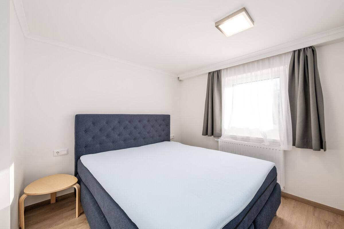 Gemütliches Schlafzimmer mit Doppelbett, Holzboden und Fenster für natürliches Licht.